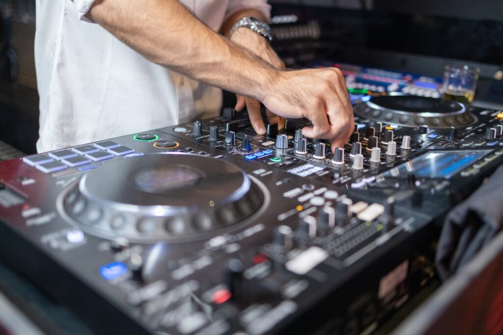 RAS Events, artistas, DJs y performers para eventos en Castellón. Las manos de un DJ ajustando el mezclador de música en un evento.